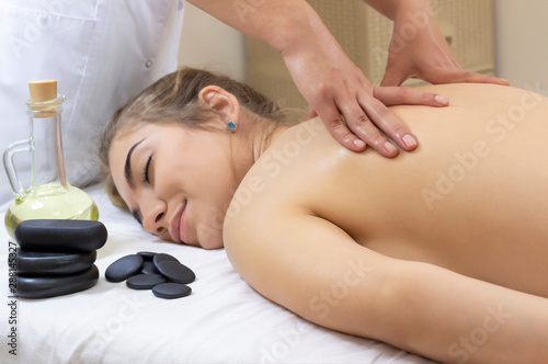 Spa Hot Stone Massage. Stone treatment. Woman getting a hot stone massage at a day spa. beautiful girl
