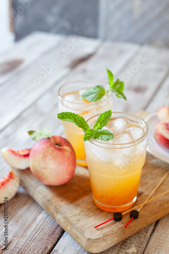 Peach cocktail with mint on white wooden background
