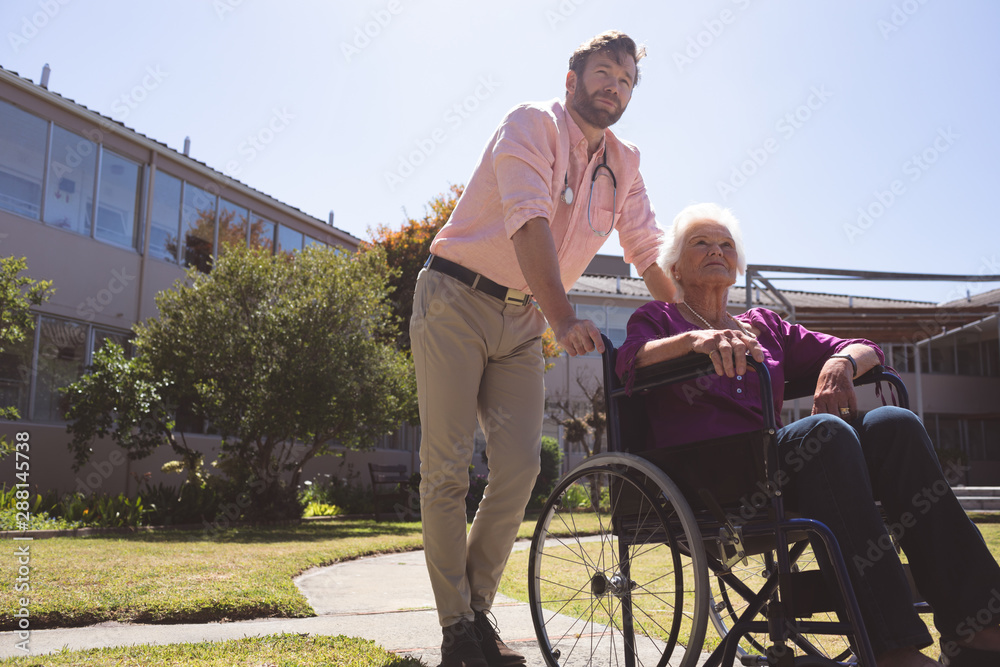 Male doctor caring disabled senior patient women in wheelchair