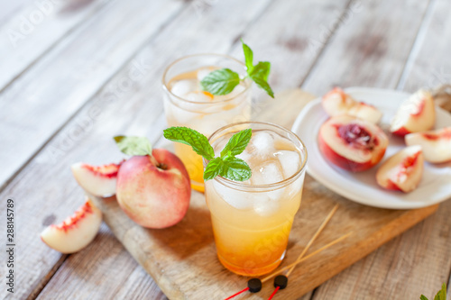 Peach cocktail with mint on white wooden background