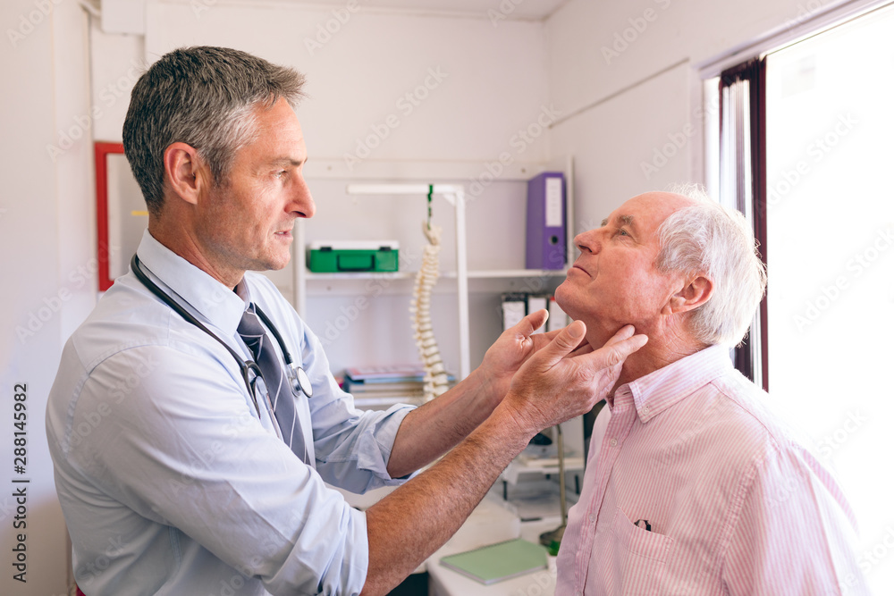 Fototapeta premium Matured male doctor checking senior man in clinic 