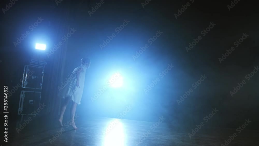 a young girl in a white dress dances a modern ballet on the stage with ...