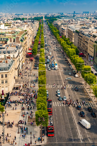 Great aerial portrait view of the famous Avenue des Champs-Élysées in Paris on a nice sunny day with a blue sky at the horizon. People walking along the shops or crossing at the crosswalk.