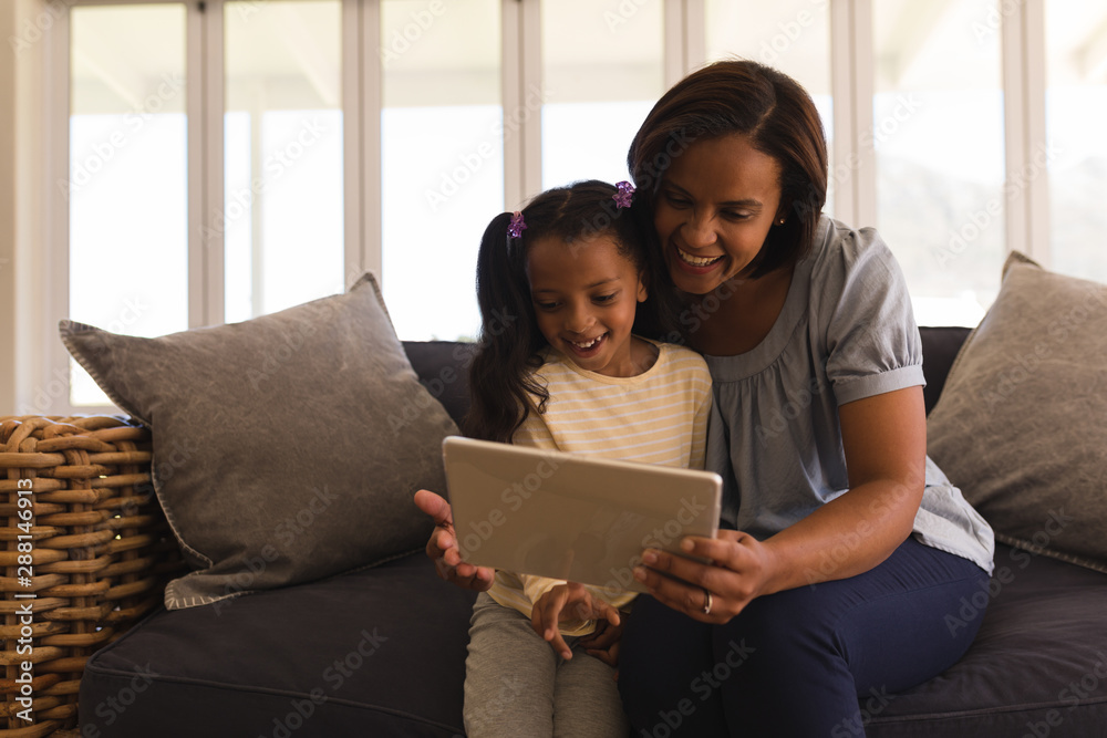 Mother and daughter using digital tablet in living room Mother and daughter using digital tablet in living room