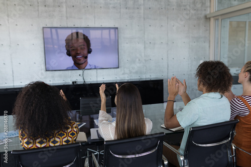 Business colleagues applauding while attending a video call in a conference room