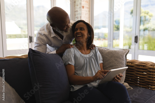 Senior couple using digital tablet in living room at home