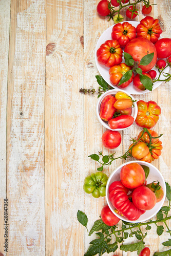 Mix of tomatoes background. Beautiful juicy organic red tomatoes on white wooden table background. Clean eating concept. Copy space, flat lay..