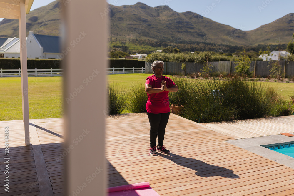 Obraz premium Senior woman performing yoga in the backyard of home