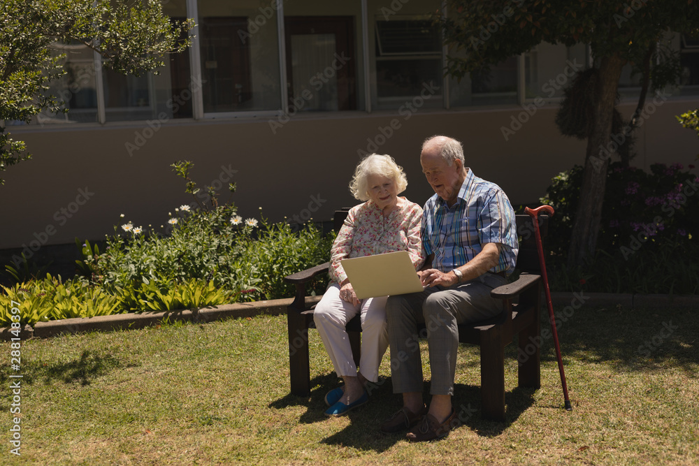 Front view of senior couple using laptop in garden