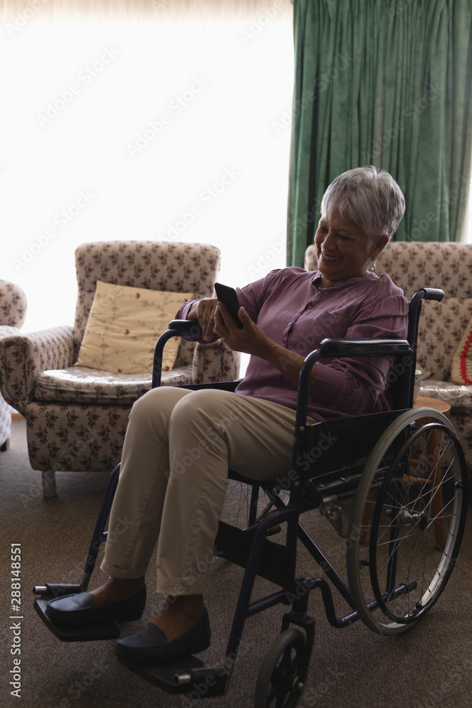 Disabled senior woman using mobile phone in living room Disabled senior woman using mobile phone in living room