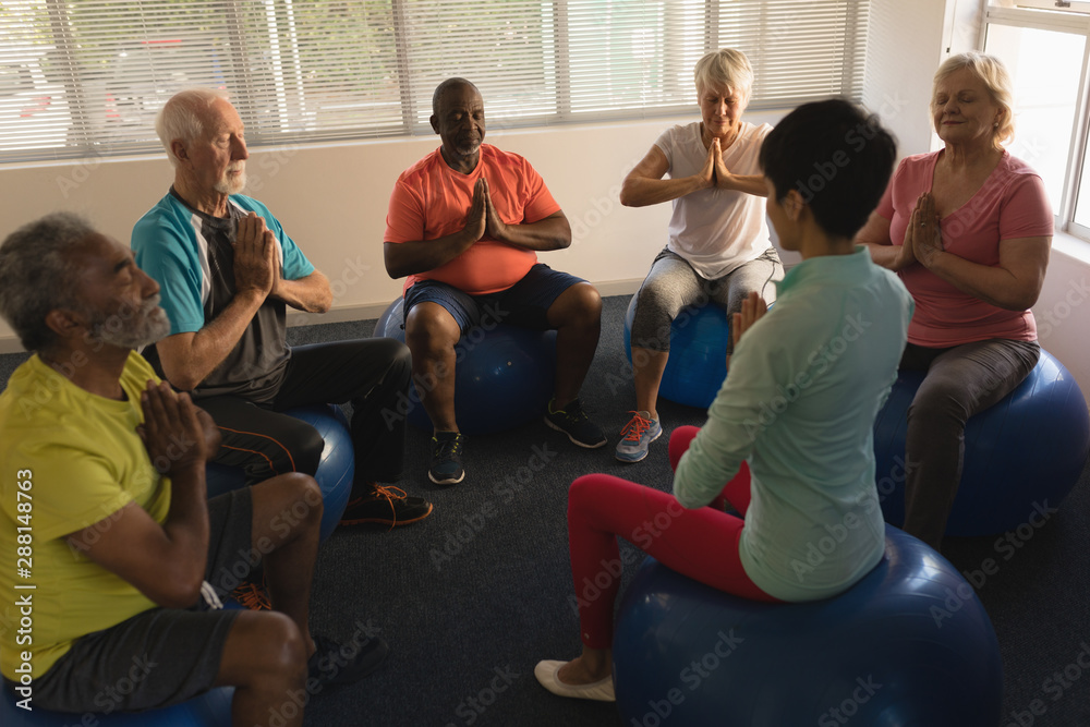 Female trainer training senior people in performing yoga Female trainer training senior people in performing yoga