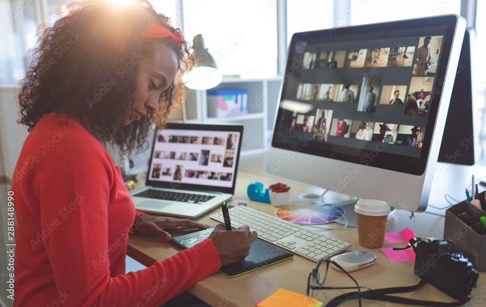 Female graphic designer working on graphic tablet at desk Female graphic designer working on graphic tablet at desk