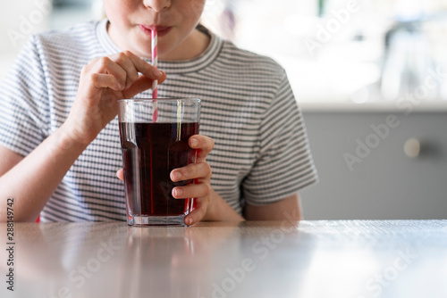 Obraz na plátně Close Up Of Girl Drinking Sugary Fizzy Soda From Glass With Straw