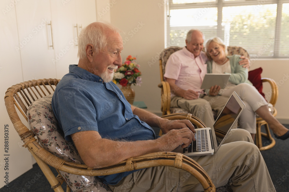 Senior man using laptop while senor couple using digital tablet at nursing home Senior man using laptop while senor couple using digital tablet at nursing home