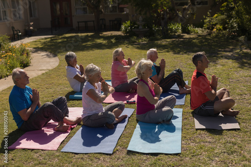Trainer training senior people in performing yoga