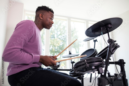 Teenage Boy Having Fun Playing Electronic Drum Kit At Home