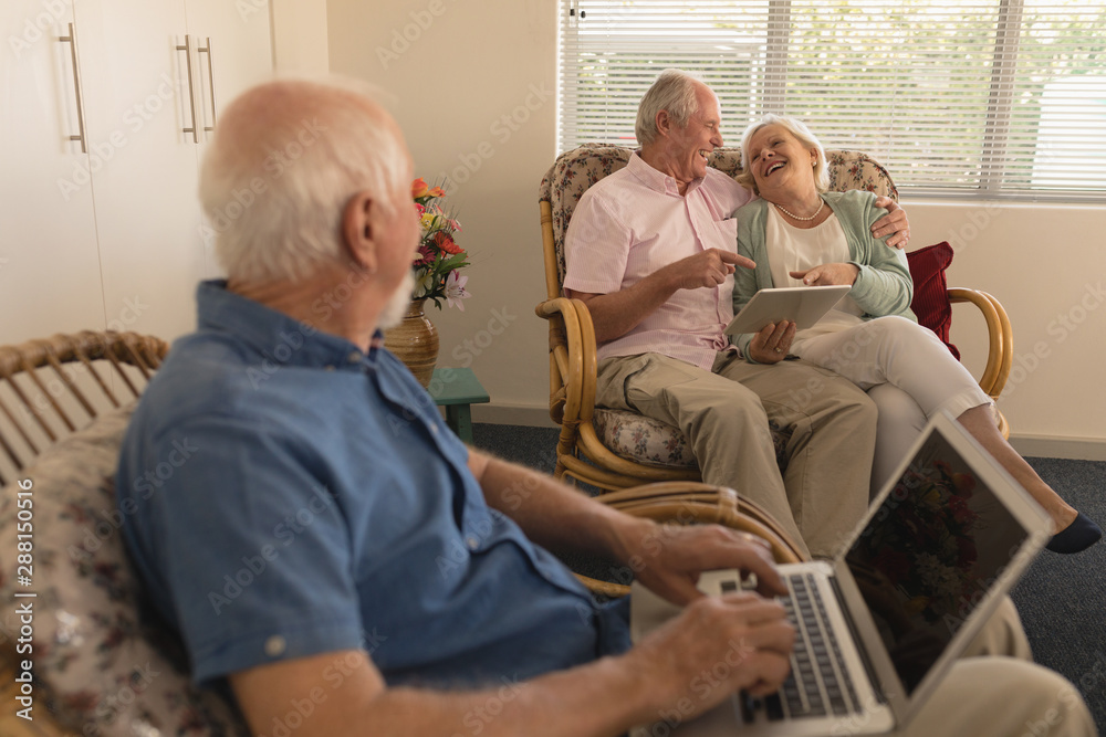 Obraz premium Senior man using laptop while senor couple using digital tablet at nursing home