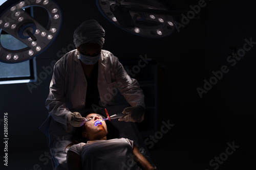 Żeński dentysta egzamininuje pacjenta z stomatologicznym leczy światłem w klinice