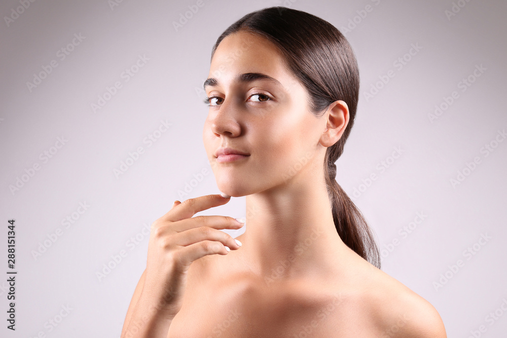 Portrait of young beautiful woman showing her perfectly clean face skin. Female with long black hair tied in ponytail touching her face showing skincare results. Close up, copy space background. Portrait of young beautiful woman showing her perfectly clean face skin. Female with long black hair tied in ponytail touching her face showing skincare results. Close up, copy space background.
