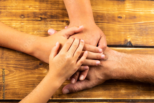 family hands on wooden background