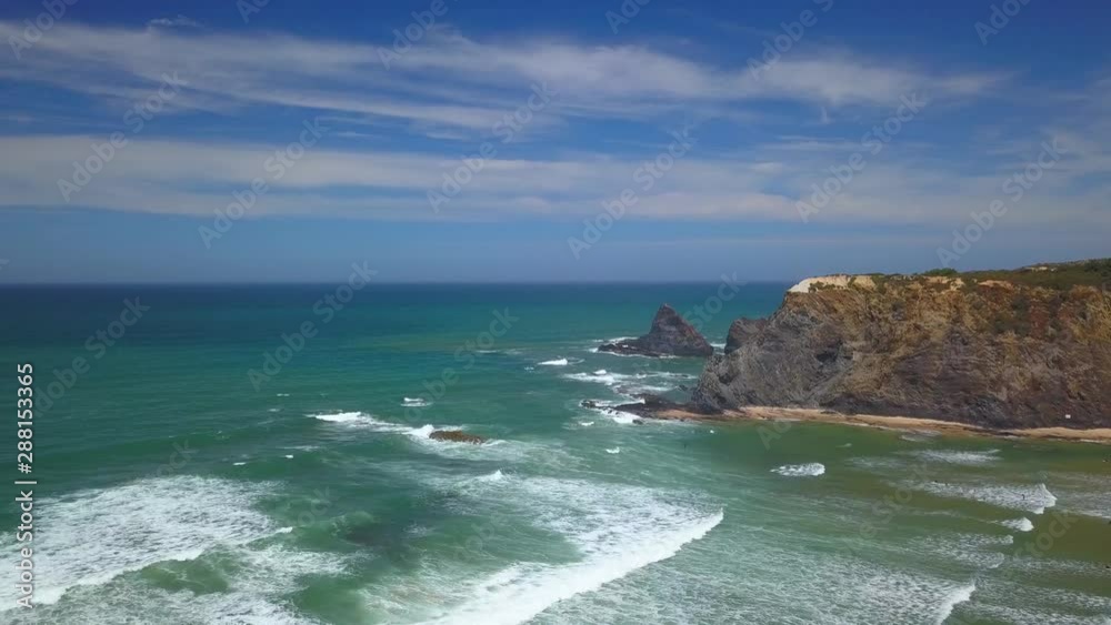 Aerial, drone shot, over waves, towards the rocky coast of the Atlantic shore, on a sunny day, in Vicentine coast national park, in Aljezur, Algarve, Portugal Aerial, drone shot, over waves, towards the rocky coast of the Atlantic shore, on a sunny day, in Vicentine coast national park, in Aljezur, Algarve, Portugal