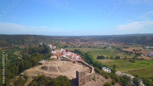 Aerial, rising, drone shot, tilting over the Aljezur castle, revealing the village, on a sunny day, in Vicentine coast national park, in Algarve, Portugal photo