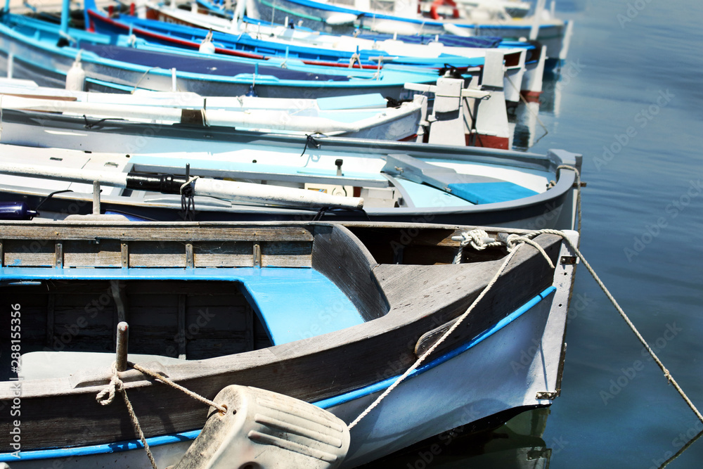 Row of blue fishing boats resting on blue water on sunny day Row of blue fishing boats resting on blue water on sunny day