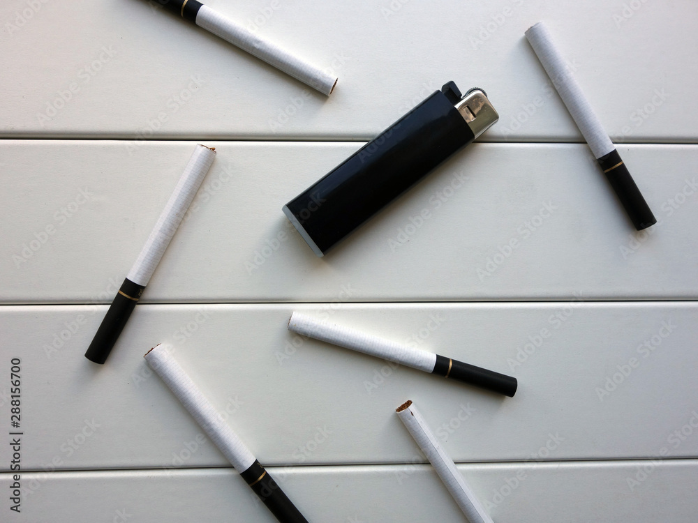 Cigarettes and a lighter scattered on a white board background, a smoker's kit Cigarettes and a lighter scattered on a white board background, a smoker's kit