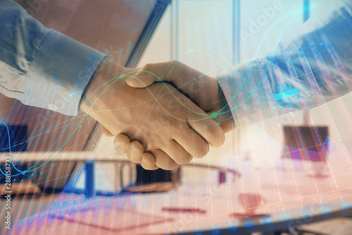 Multi exposure of financial graph on office background with two businessmen handshake. Concept of success in business