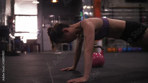 Side view of Asian female athlete is doing push-ups in gym Sexy Chinese woman is doing her Cross Fitness Workout dedicatedly photo