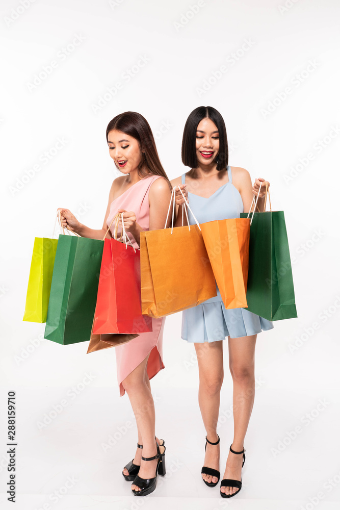 Excited happy young asia women friends posing white background holding shopping bags looking bag Excited happy young asia women friends posing white background holding shopping bags looking bag