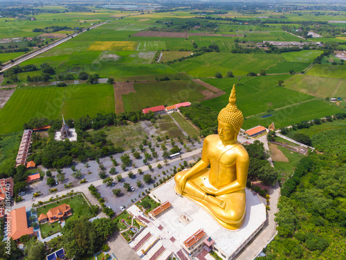 Golden buddha statue in buddhism temple with rice plantation photo