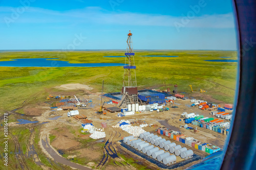 Drilling rig and equipment at an oil field in the northern tundra. Top view from a helicopter. Green summer tundra with lakes beyond the Arctic Circle. photo