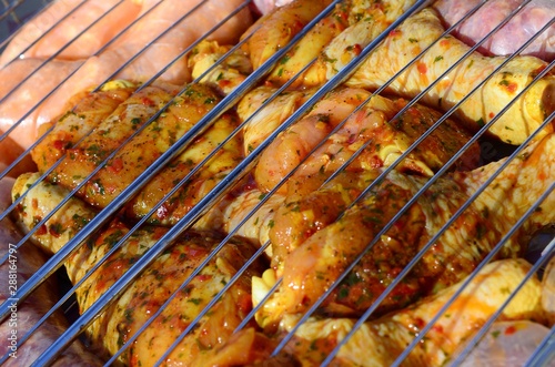 Marinated chicken legs on hot BBQ charcoal field grill photo