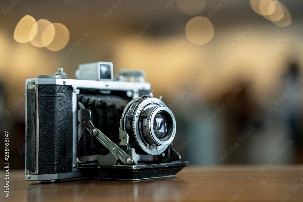 Retro film photo camera isolated on blurred background at light bokeh..