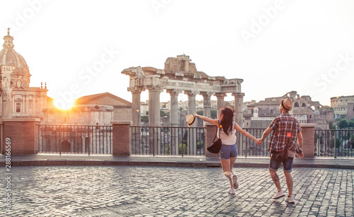Canvas Print Young couple tourist walking pointing towards Roman Forum at sunrise