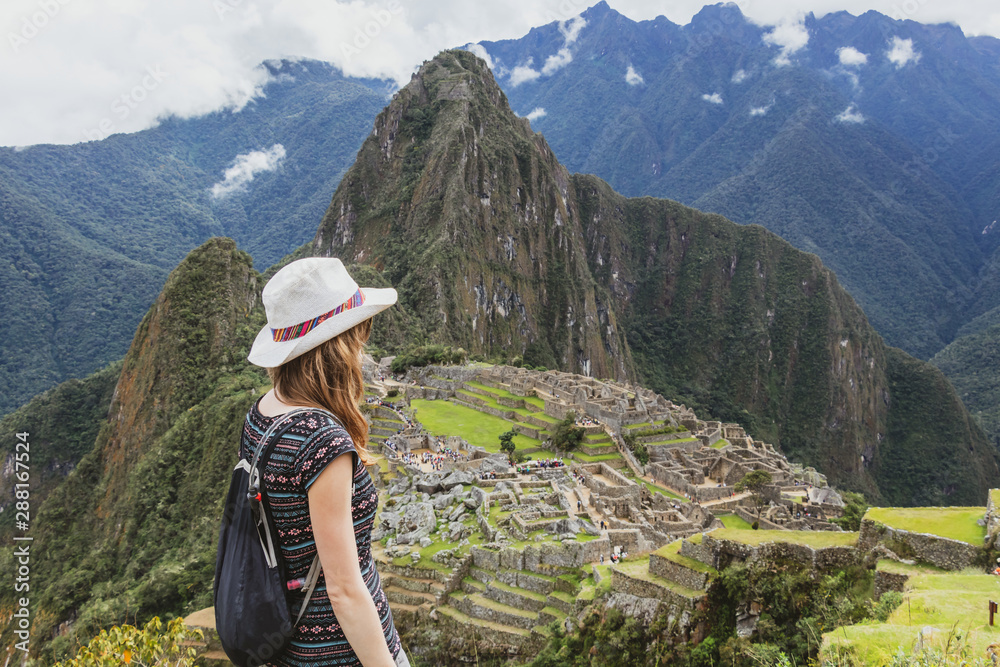 Young caucasian happy woman in Machu Picchu mountain and looking away in Peru. Back view with copy space