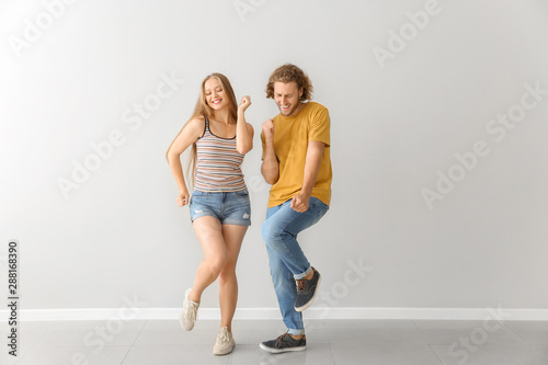 Cool young couple dancing against white wall