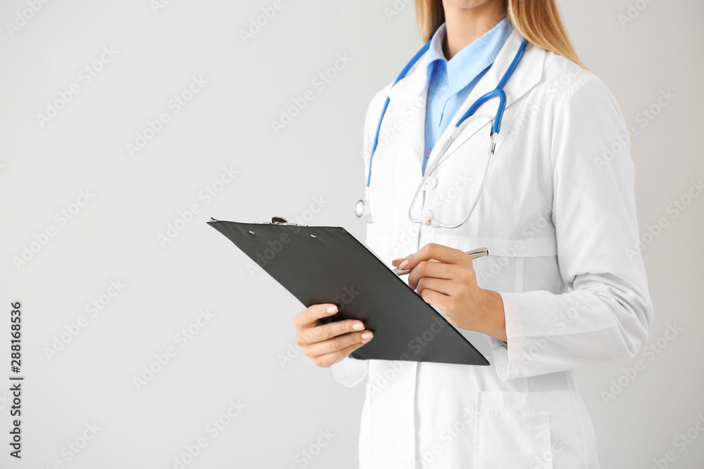 Female doctor with stethoscope and clipboard on light background Female doctor with stethoscope and clipboard on light background