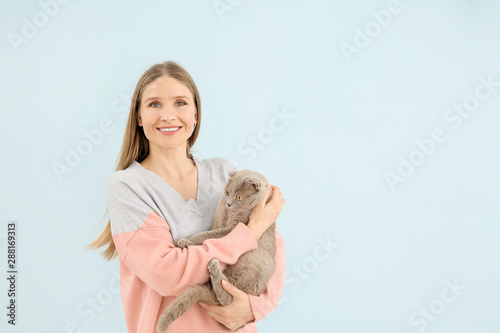 Beautiful woman with cute cat on color background