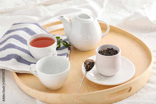 Tray with hot tea on bed in morning