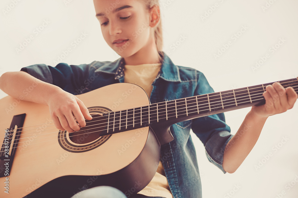 Fototapeta premium Teen girl attentively playing guitar