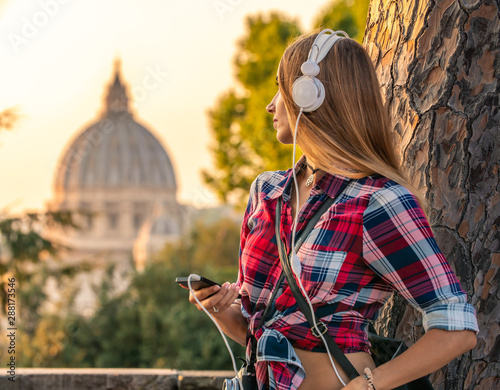 Photography Beautiful young blonde woman with long hair listening to music with white headpones and smartphone