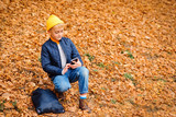 Handsome preteen boy using smartphone on a walk in autumn park. Stylish schoolboy walking after school. People, technology, fashion, lifestyle.