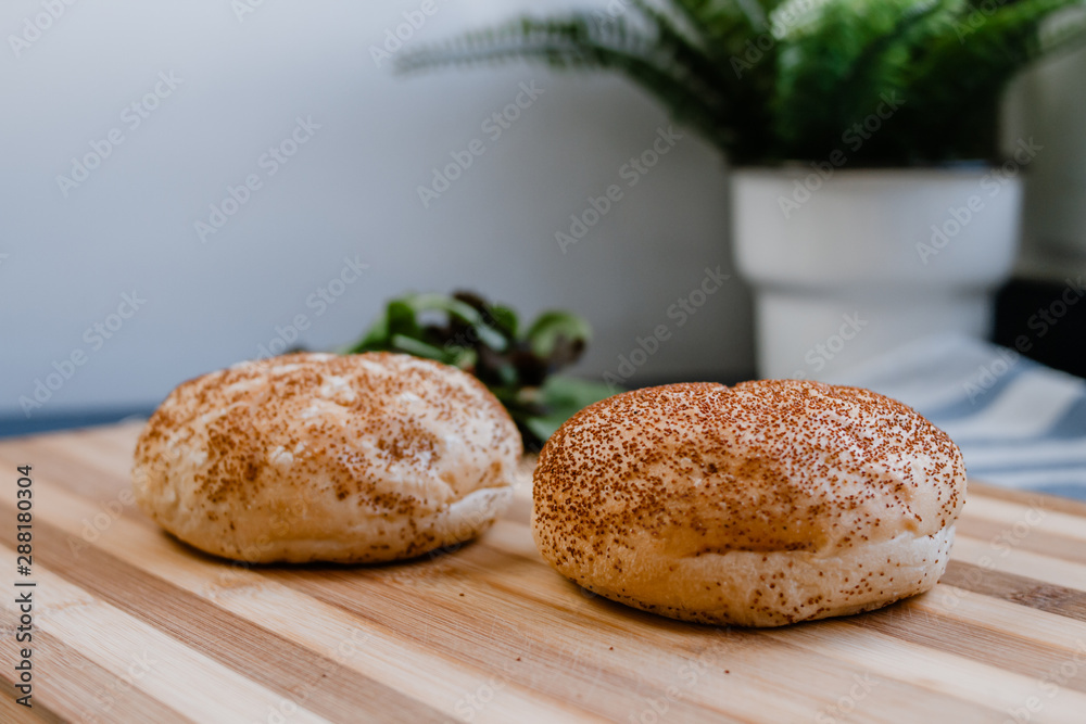 Two hamburger bread in a wooden cutting board
