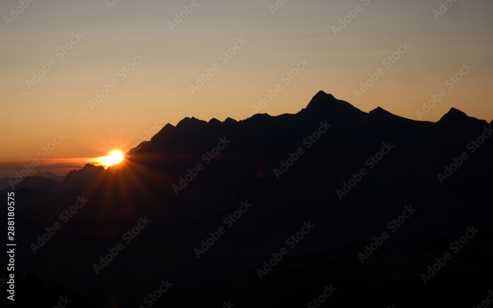 Beautiful sunrise in the swiss mountains, silhouette of mountain peaks backlit in the early morning.