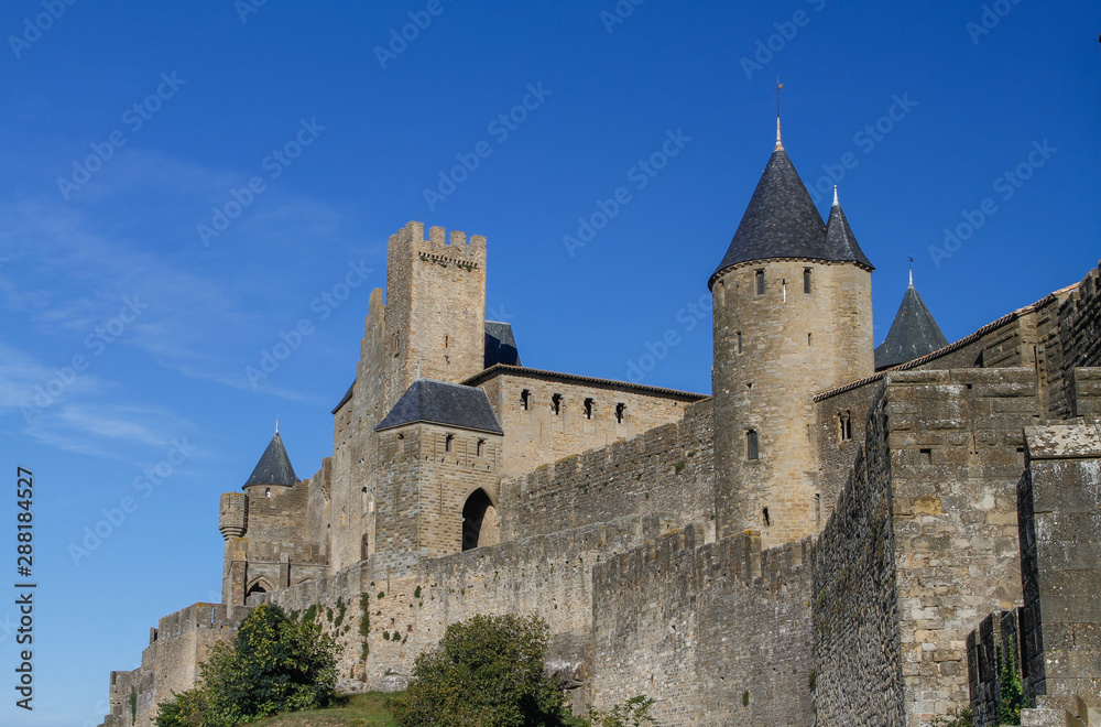Carcassonne, ancient fortified city on the top of a hill in Languedoc-Roussillon on the Aude River, France, Europe. Crenellated walls and watchtowers blue sky