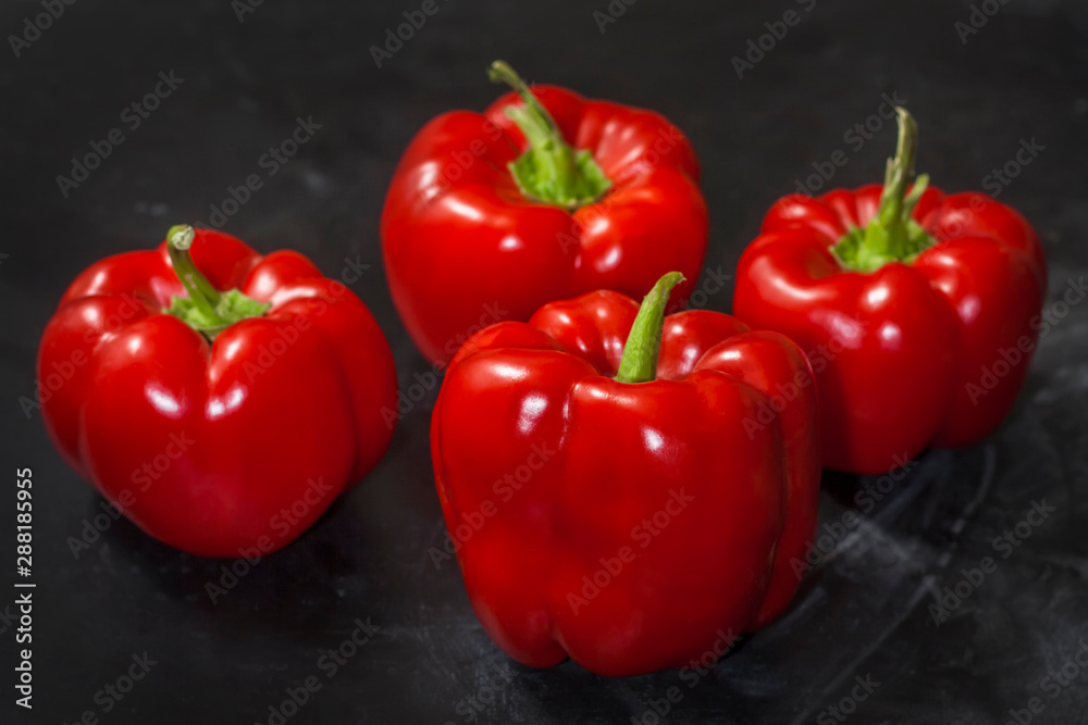 Fresh four red peppers on a black background in the center of the frame. Fresh four red peppers on a black background in the center of the frame.