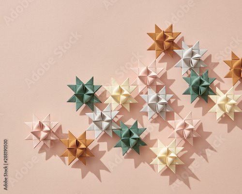 Holiday composition of different paper origami stars on a beige background with copy space. Layout for the new year or Christmas. Flat lay