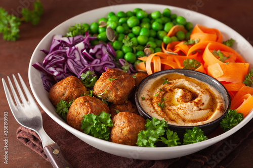 healthy vegan lunch bowl with falafel hummus carrot ribbons cabbage and peas